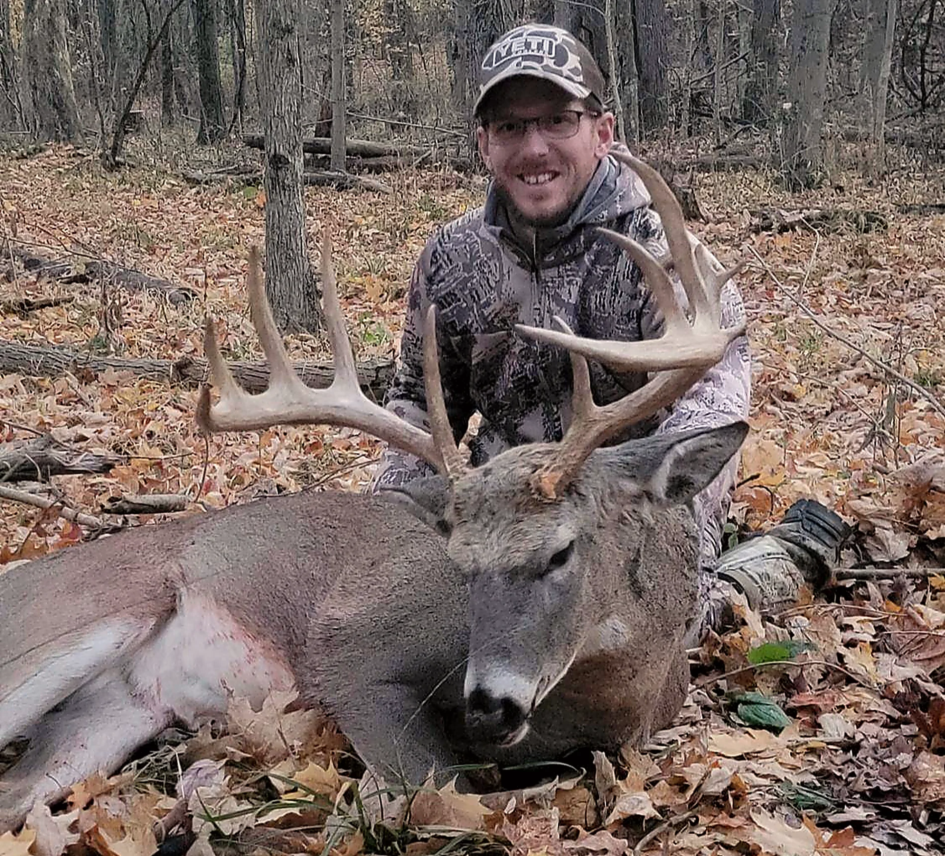 Hunter with an Illinois whitetail buck in leaf litter at Bigger Bucks Outfitters