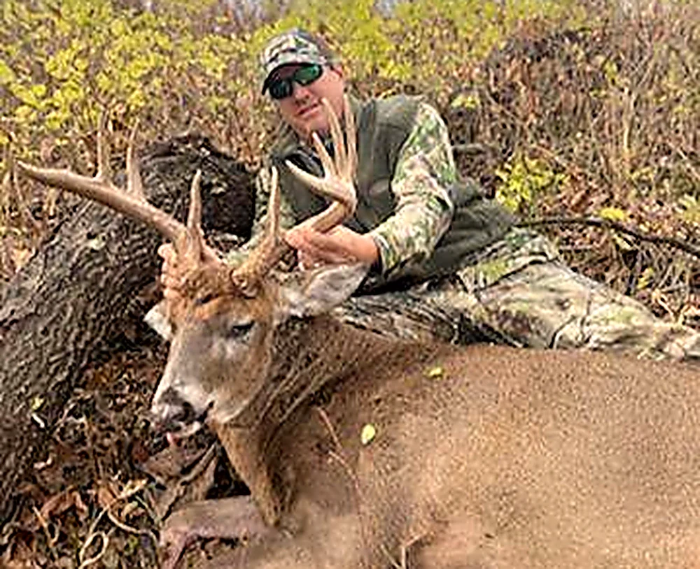 Hunter with an Illinois whitetail buck beside an oak
